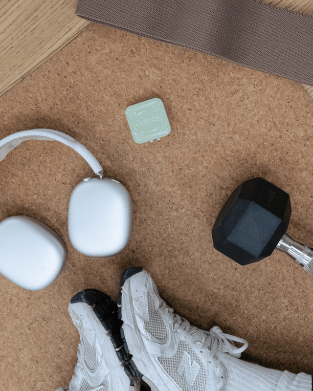 workout mat with dumbbell, headphones, jones tin, and sneakers