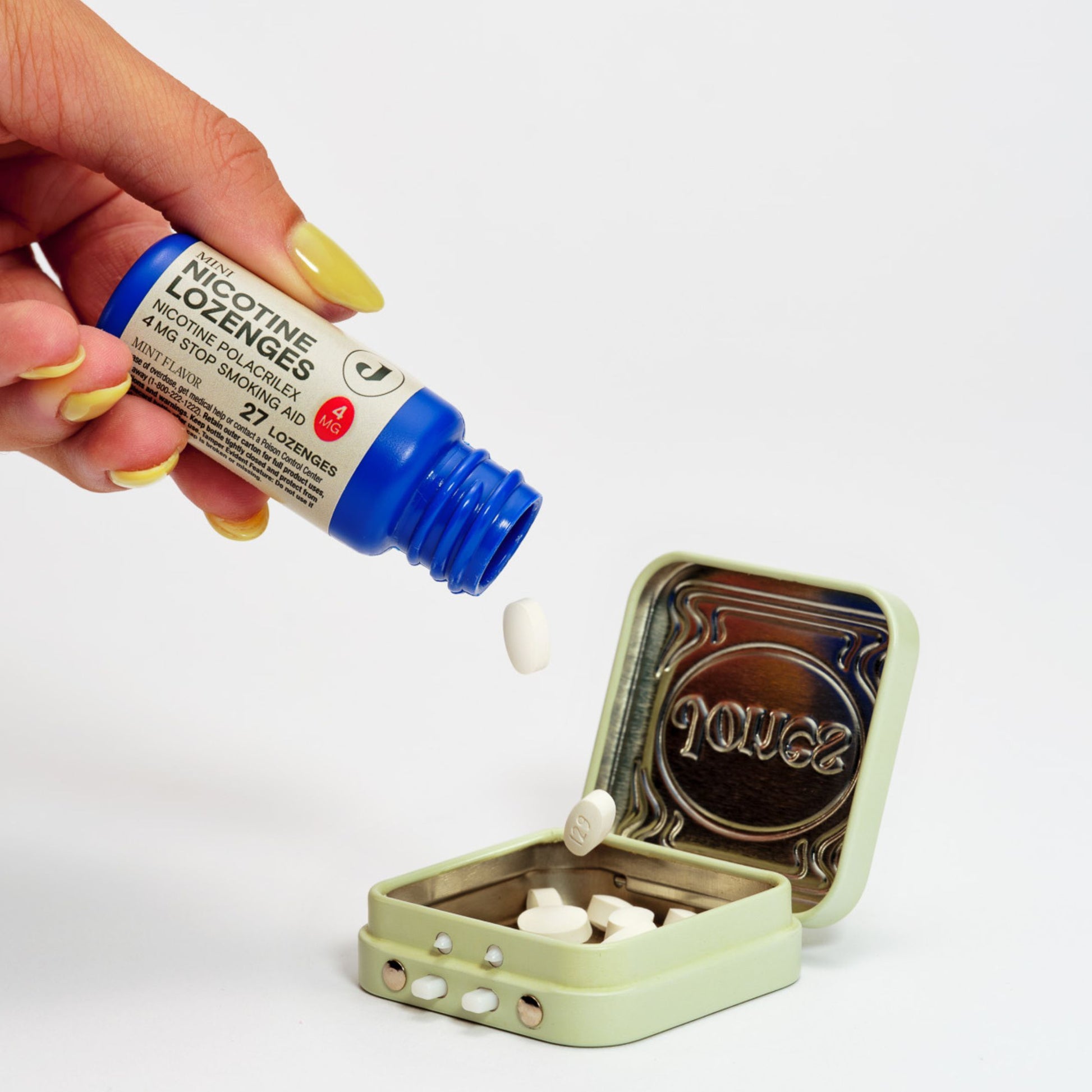 A hand dispenses FDA-approved 4mg Lozenge nicotine lozenges from a blue bottle into a small tin box on a white background, providing an effective solution for managing cravings within a comprehensive nicotine replacement therapy plan.