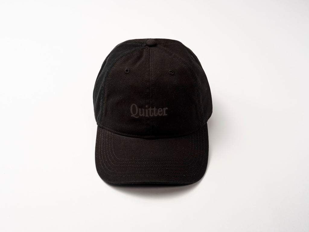 The Quit with Jones "Quitter Cap (Copy)" is a black cotton twill baseball cap with embroidered "Quitter" on the front, shown against a white background.