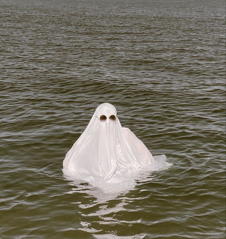 person in the water with a ghost costume on with sunglasses