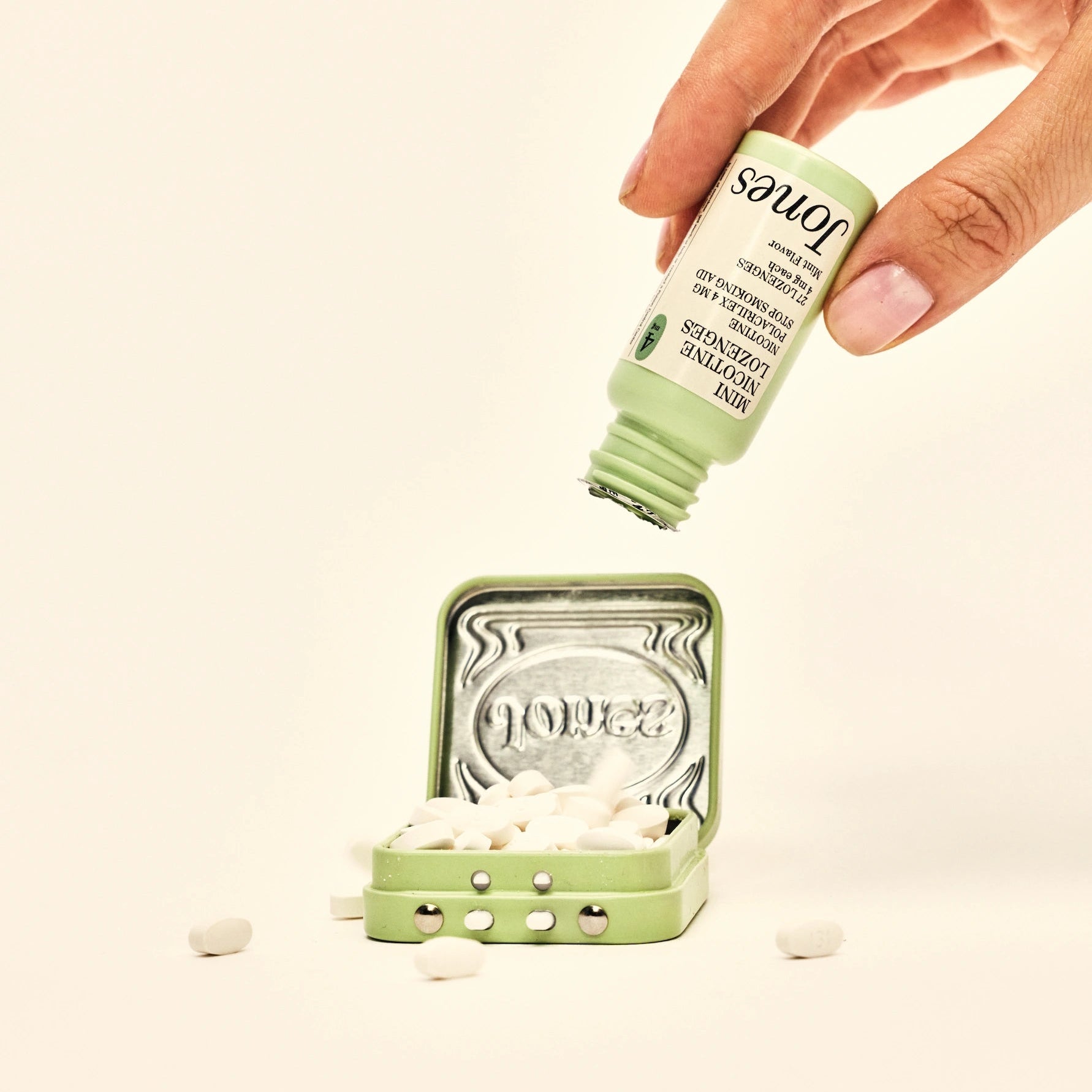 Five green boxes labeled "Jones Habit Kicker" are stacked geometrically on a beige background. Three white lozenges, part of this nicotine quit kit, are displayed in front. The boxes have minimalist text and icons.