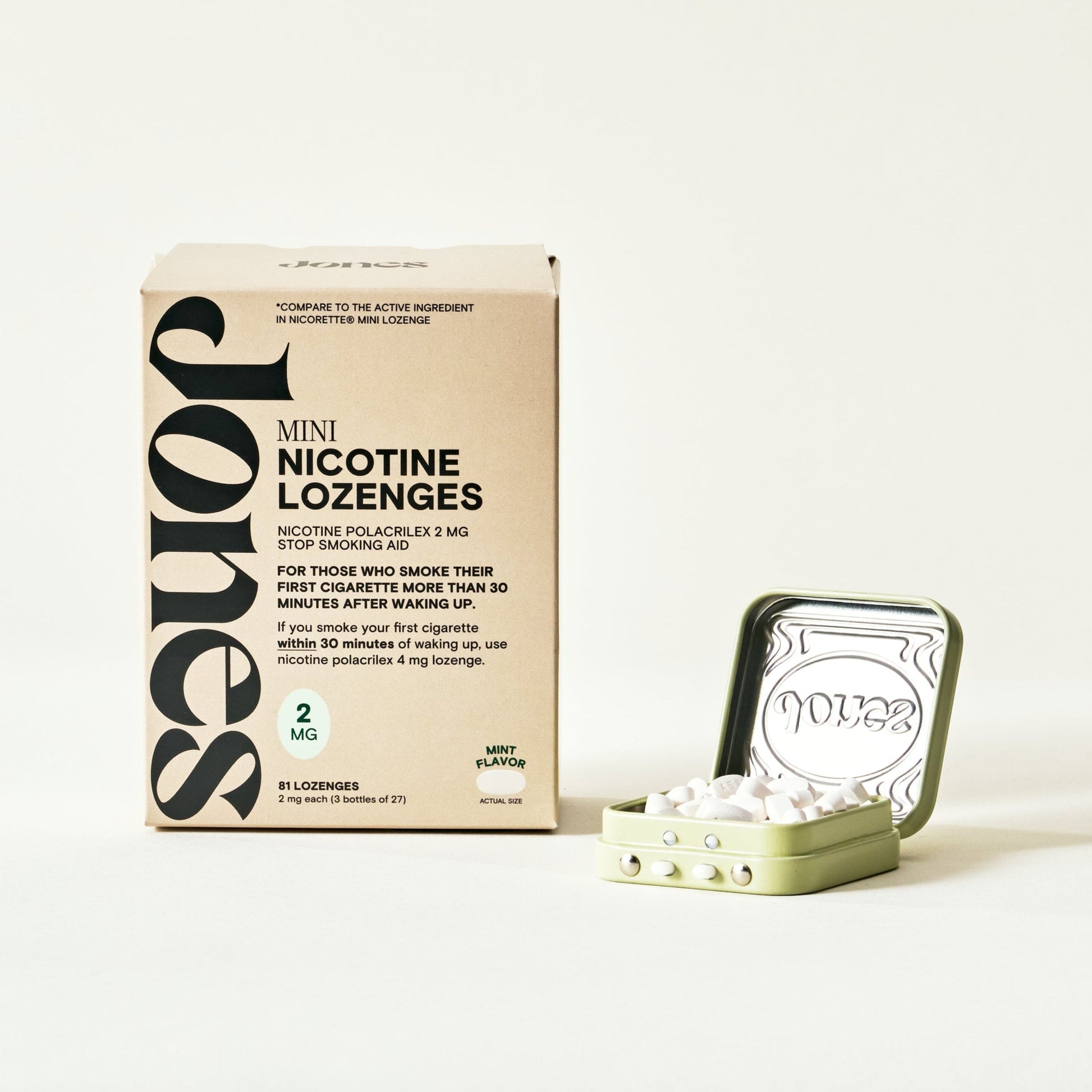 A beige box labeled “Quit with Jones 2mg Nicotine Mint” stands upright next to an open mint-green tin, both featuring minimalist packaging with dosage details, designed for nicotine replacement therapy on a plain white background.