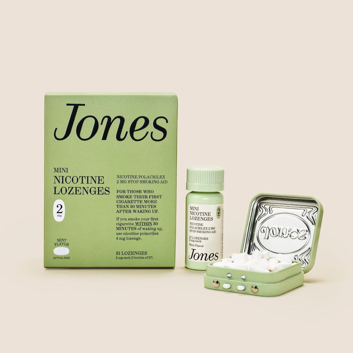 Five green boxes labeled "Jones Habit Kicker" are stacked geometrically on a beige background. Three white lozenges, part of this nicotine quit kit, are displayed in front. The boxes have minimalist text and icons.