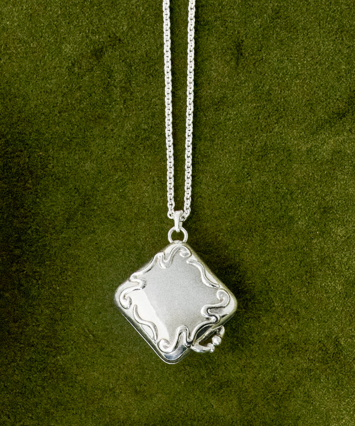 The Quit with Jones Sterling Chain is a sterling silver necklace featuring a thin chain and a square pendant with wavy abstract detailing, making it beautifully wearable for any occasion.