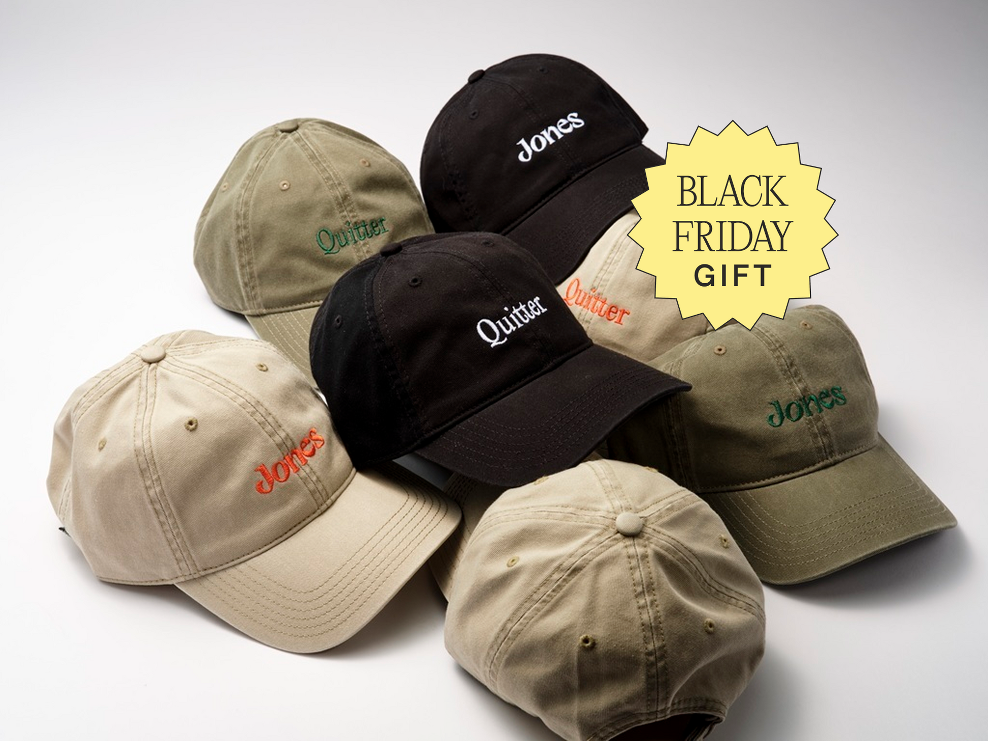 Six Jones baseball caps in beige, olive, and black display embroidered “Jones” and “Quitter.” A yellow "BLACK FRIDAY GIFT" label is shown. Bundle your order for a Jones Surprise Hat. All caps are arranged on a white surface.