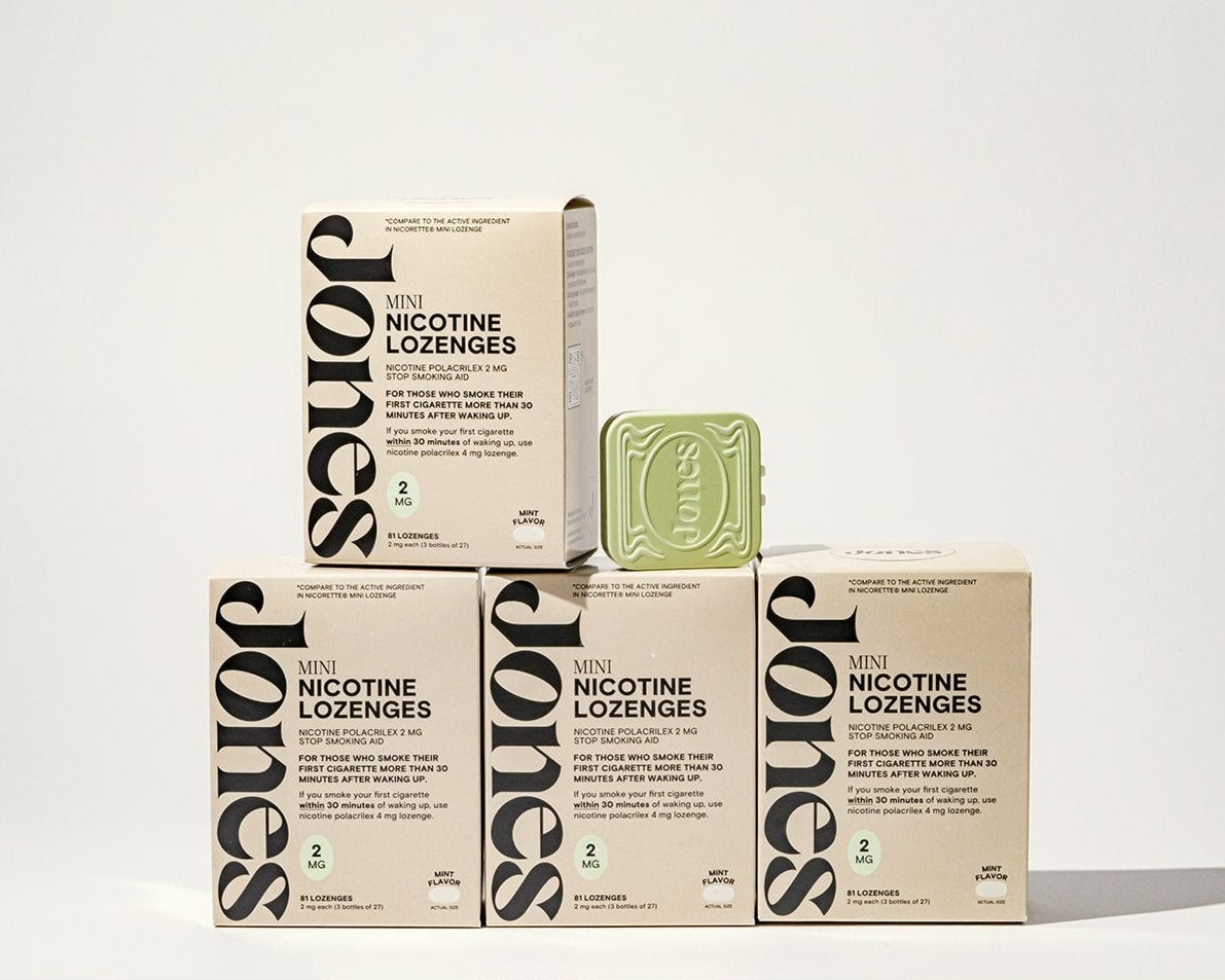 Five beige boxes of Jones Low Dependency Quit Kit are stacked in a pyramid, topped by a pale green tin embossed with "Jones." The arrangement sits against a plain, well-lit background.