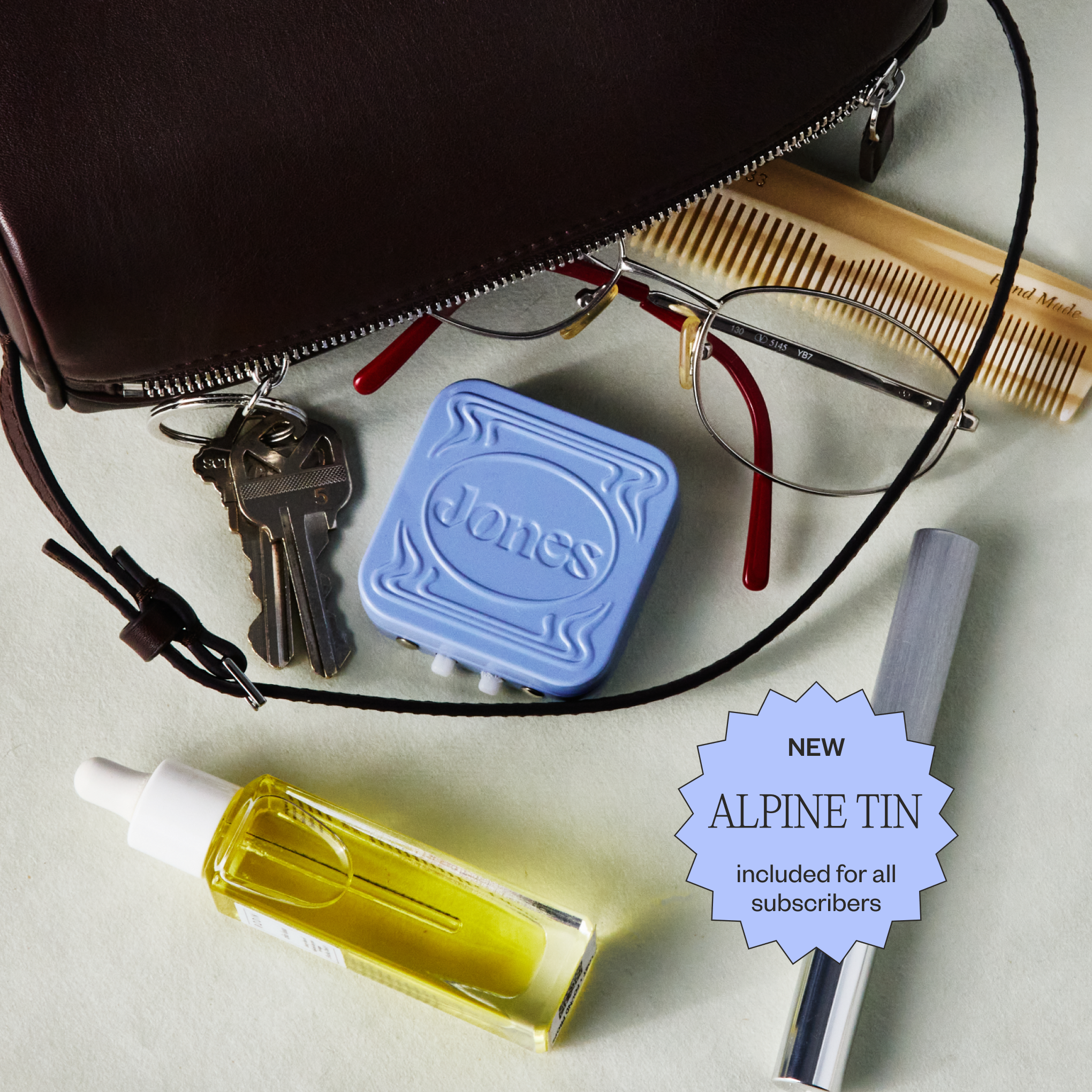 A hand holding a small square metal tin with embellishments labeled Jones that contains FDA-approved Jones nicotine replacement therapy lozenges and a cell phone screen showing an app to quit vaping by Jones with money saved, streak, and daily nicotine tracking.