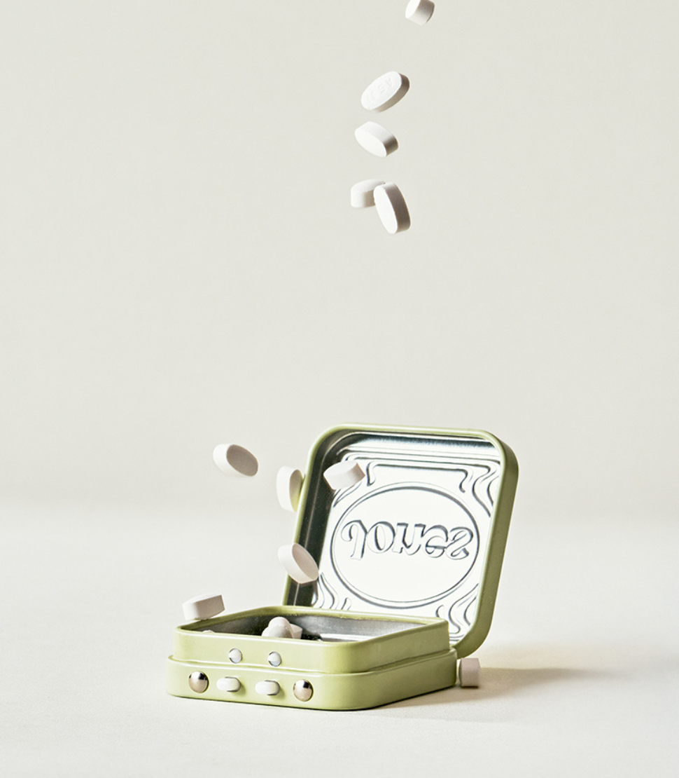 A beige box labeled “Quit with Jones 2mg Nicotine Mint” stands upright next to an open mint-green tin, both featuring minimalist packaging with dosage details, designed for nicotine replacement therapy on a plain white background.